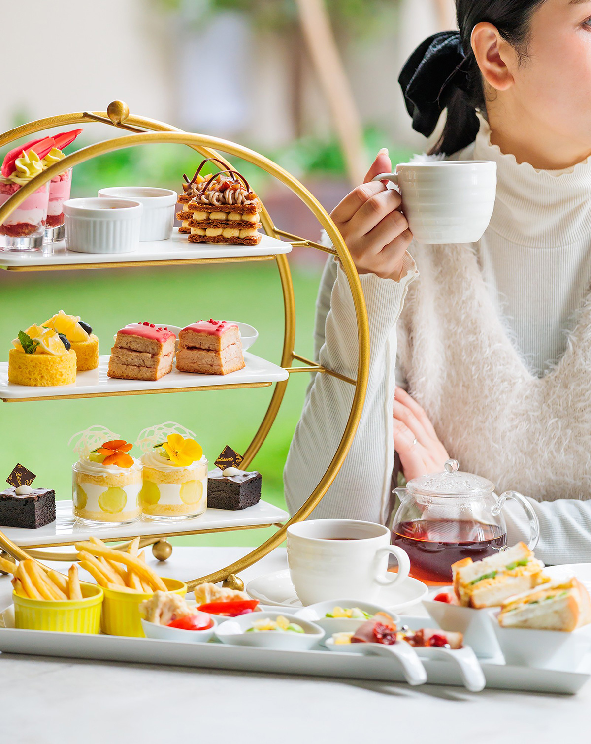 ティーカップ片手にアフタヌーンティーを優雅に楽しむ女性イメージ