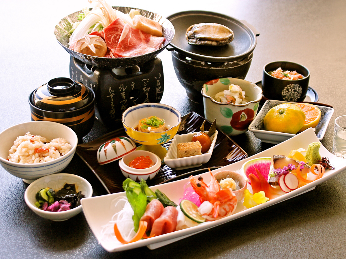 伊豆・畑毛温泉大仙家で提供される夕食「華やぎ会席」。活き鮑の踊り焼き・鮮魚六種盛り・牛ロースすき鍋など。11品の会席料理
