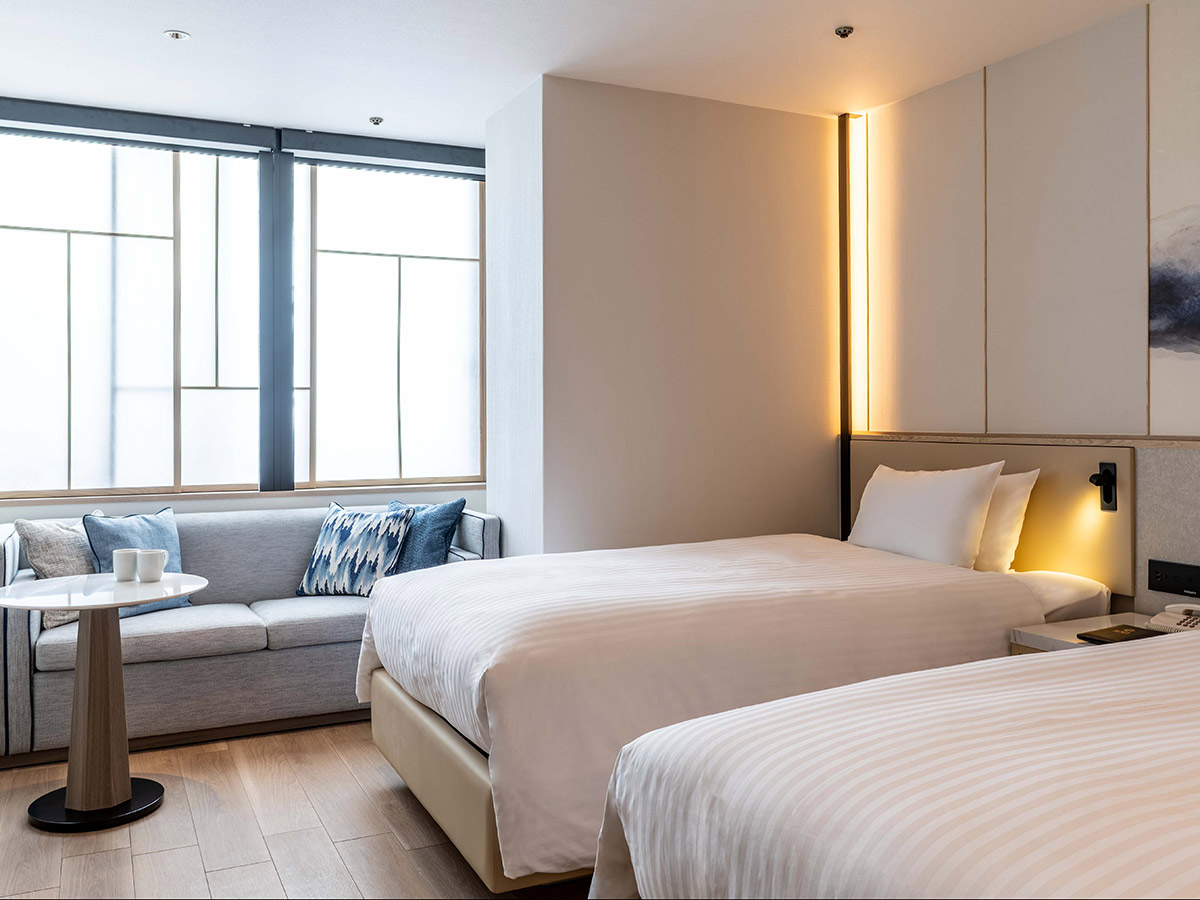 新客室ツインルームのベッドと窓とソファー