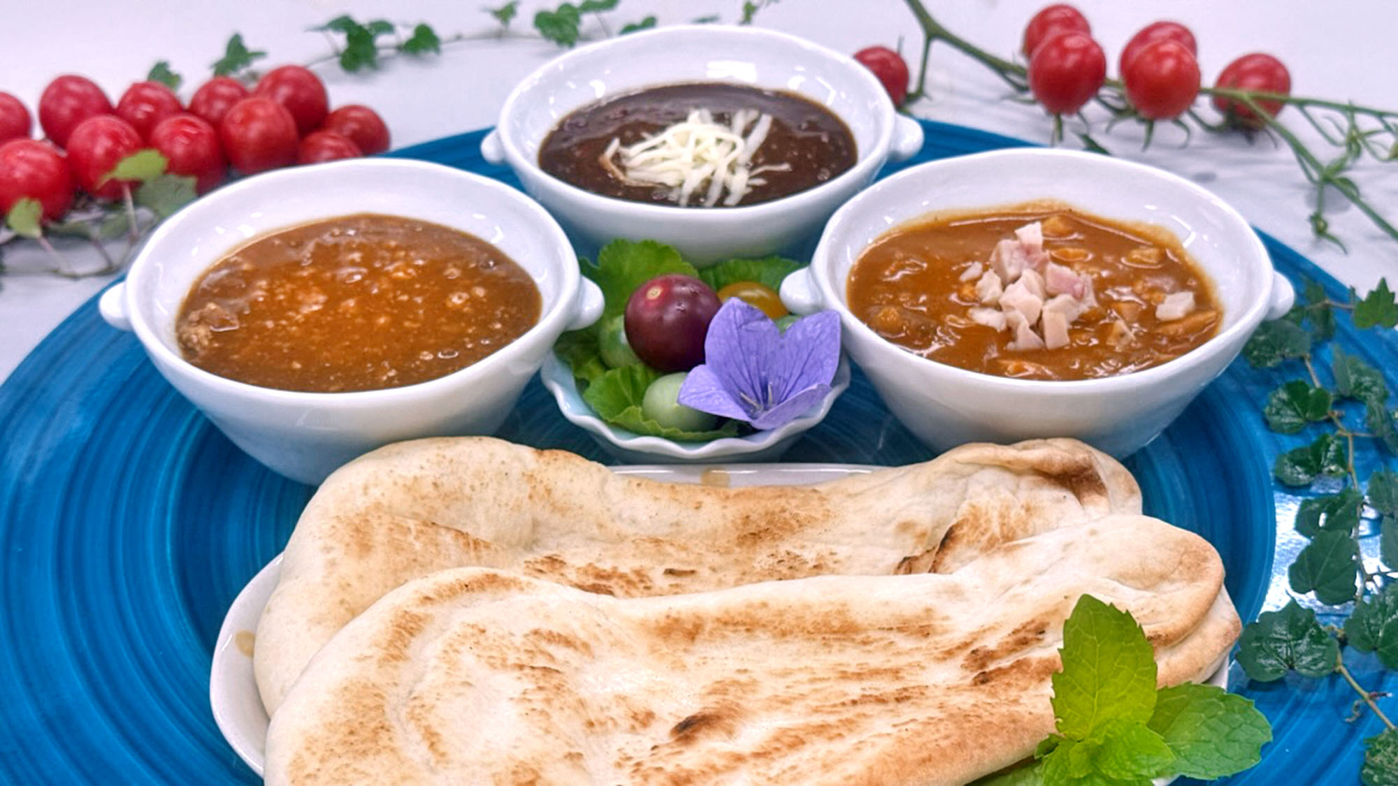 小鉢に入ったビーフ＆ポークカレー、黒胡麻ブラックカレー、チキンバターカレーと、ピザ窯で焼き上げたナン。