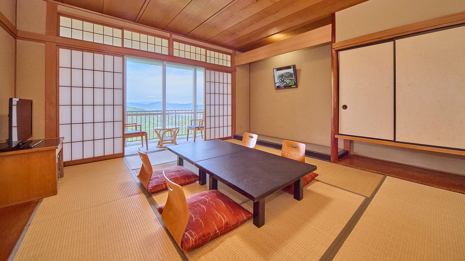 和室10畳・畳の部屋に4つの座椅子と1つの座卓と窓際に椅子2つ