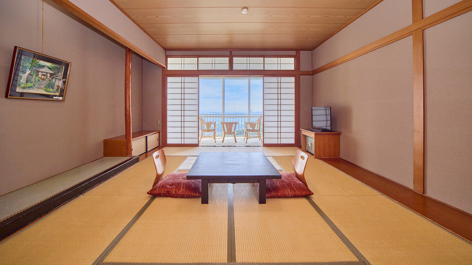 和室12畳・広い畳の部屋に2つの座椅子と1つの座卓と窓際に椅子2つ