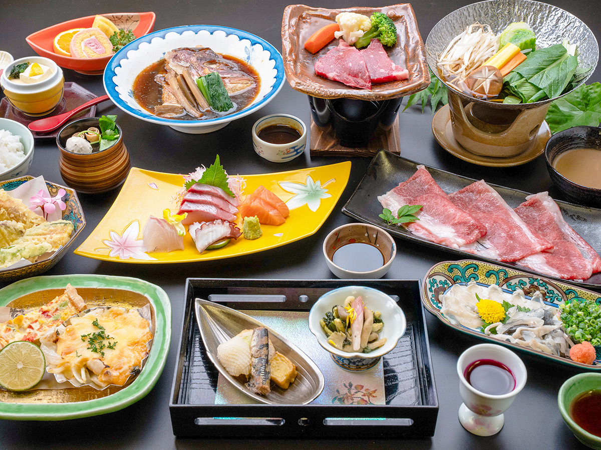 長門湯本温泉の旅館、湯本観光ホテル西京の雅会席。牛陶板焼き、牛しゃぶ鍋、鯛のあら煮など、12品の料理が並ぶ。